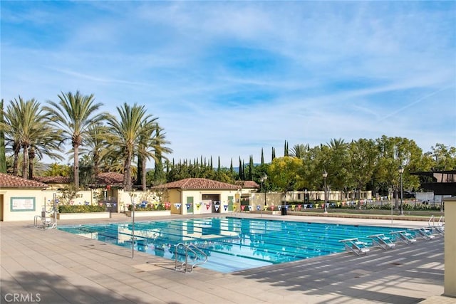 community pool featuring fence and a patio