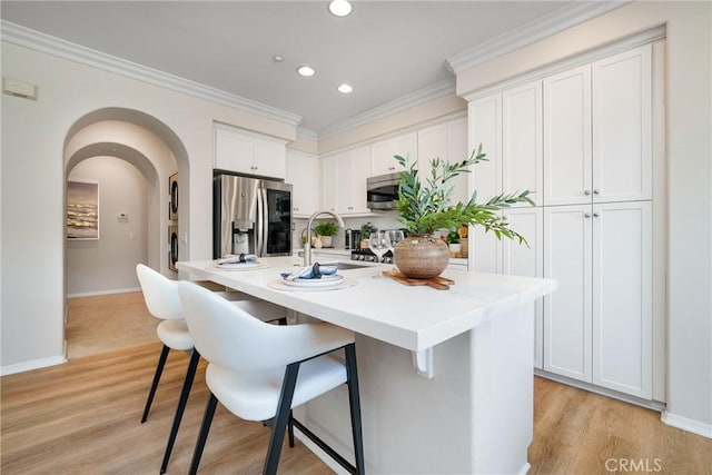 kitchen with appliances with stainless steel finishes, a breakfast bar, a sink, and ornamental molding