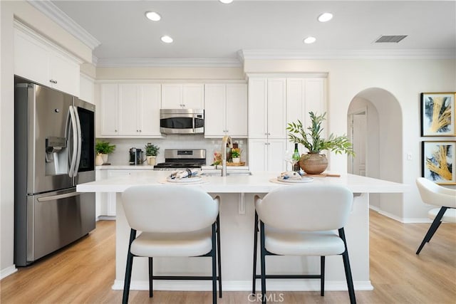 kitchen featuring a breakfast bar, stainless steel appliances, light countertops, visible vents, and a sink