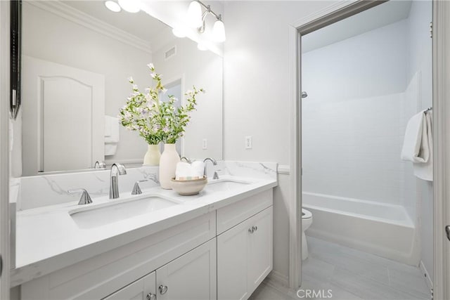 bathroom featuring toilet, a sink, visible vents, double vanity, and crown molding