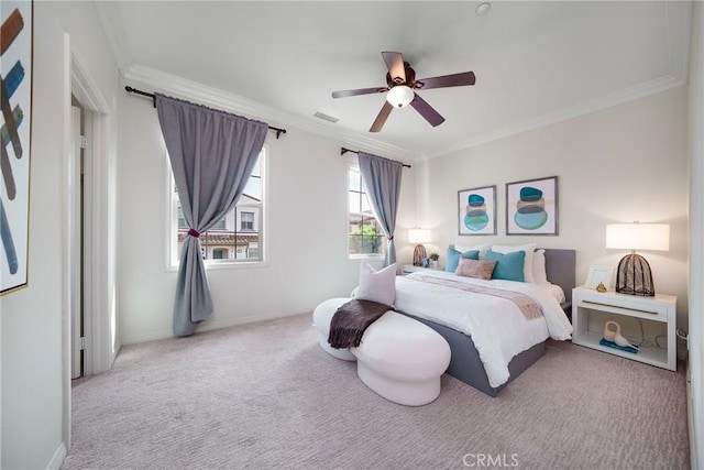 carpeted bedroom with visible vents, crown molding, baseboards, and ceiling fan