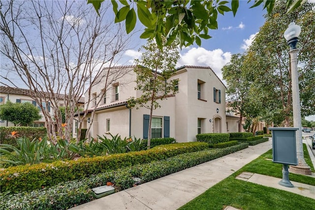 view of side of home featuring a tiled roof and stucco siding