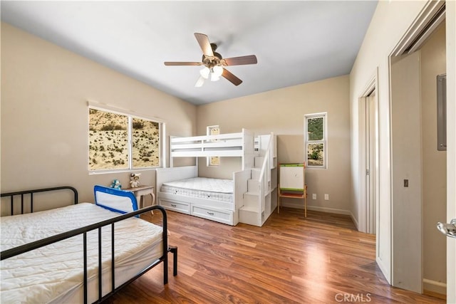 bedroom with ceiling fan, wood finished floors, and baseboards