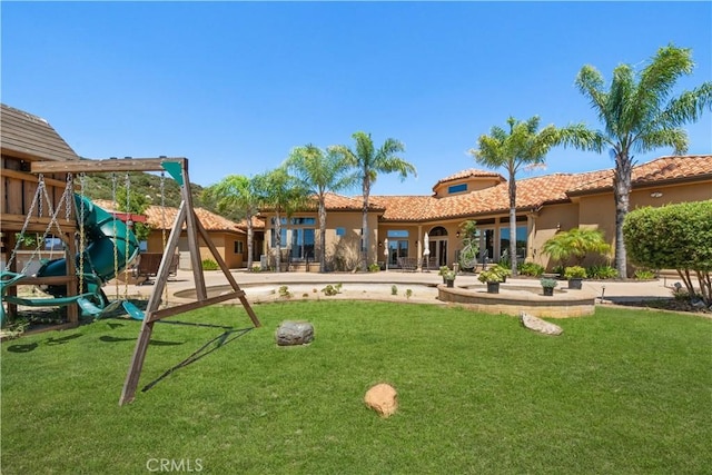 exterior space with a yard, a playground, a tiled roof, and stucco siding