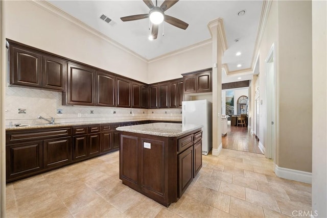 kitchen with visible vents, backsplash, a sink, and freestanding refrigerator