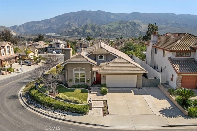 view of front of property featuring an attached garage, a mountain view, a tile roof, fence, and stucco siding