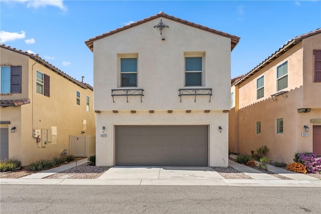 mediterranean / spanish home with concrete driveway, a tile roof, an attached garage, and stucco siding