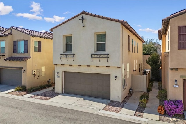 mediterranean / spanish-style home featuring an attached garage, a tile roof, concrete driveway, and stucco siding