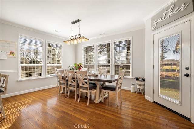 dining space with a notable chandelier, wood-type flooring, baseboards, and crown molding