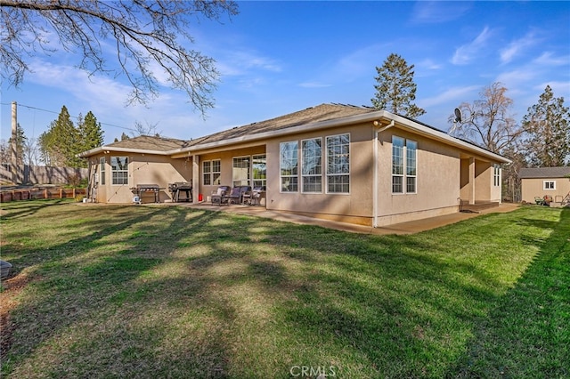 rear view of house with a patio area, a lawn, and stucco siding