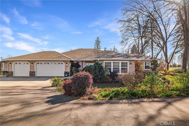 ranch-style home featuring a garage, concrete driveway, and stone siding