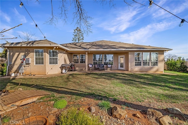 rear view of house featuring a patio area, a yard, and stucco siding