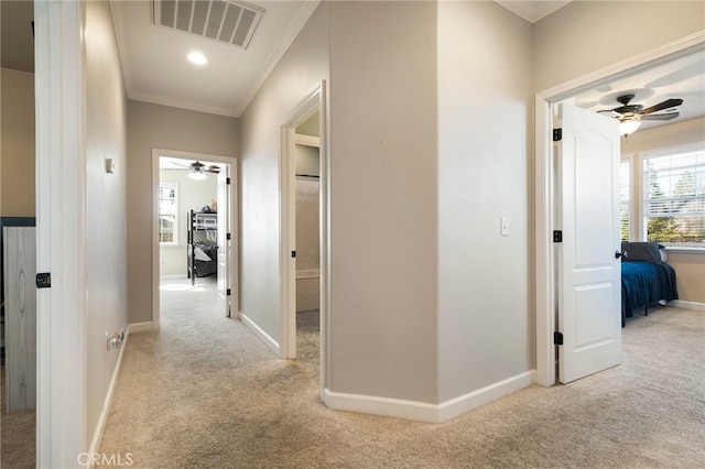 hallway featuring carpet floors, ornamental molding, visible vents, and baseboards