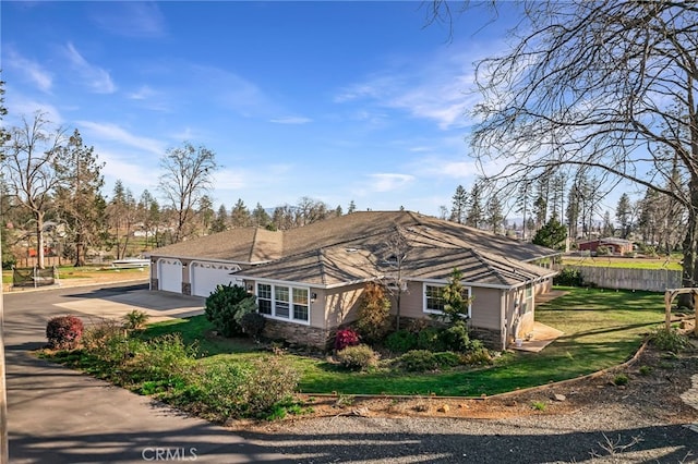 view of front of home featuring a garage, fence, driveway, stone siding, and a front lawn