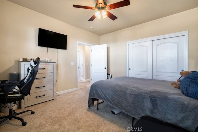 bedroom featuring baseboards, ceiling fan, a closet, and light colored carpet