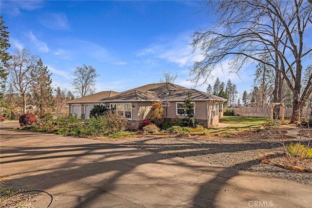 view of front of house with concrete driveway, fence, and an attached garage