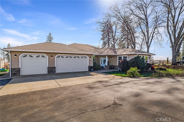 ranch-style home with a garage, stone siding, and driveway