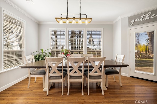 dining area with baseboards, ornamental molding, wood finished floors, and a notable chandelier