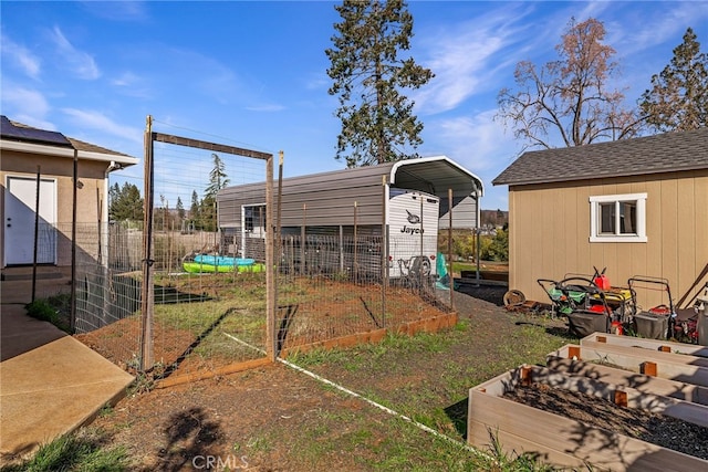 view of yard featuring fence, a vegetable garden, and a carport