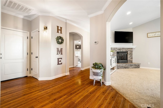 interior space featuring baseboards, visible vents, ornamental molding, wood finished floors, and a fireplace