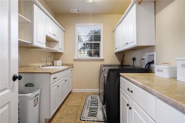 washroom with cabinet space, light tile patterned floors, visible vents, washer and dryer, and a sink