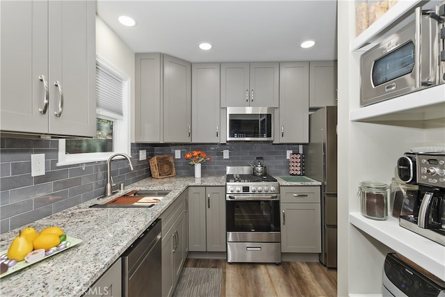 kitchen with dark wood-style floors, gray cabinets, stainless steel appliances, and a sink