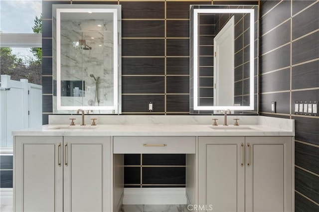 bathroom featuring double vanity, a marble finish shower, tile walls, and a sink