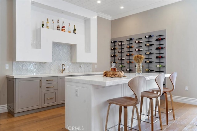 interior space with tasteful backsplash, a breakfast bar area, gray cabinets, and a center island