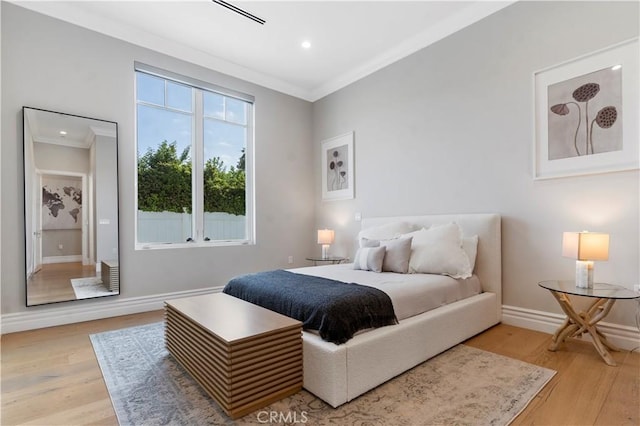 bedroom featuring light wood-style floors, crown molding, and baseboards