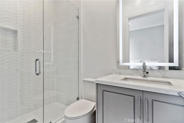 bathroom featuring a stall shower, vanity, toilet, and crown molding