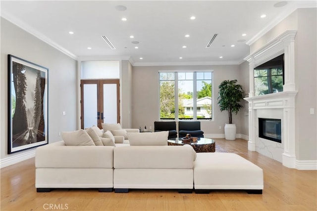 living area featuring french doors, recessed lighting, a glass covered fireplace, and crown molding