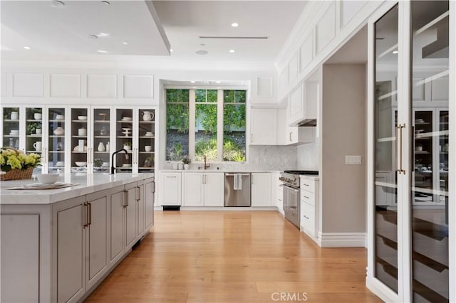 kitchen with light wood-type flooring, appliances with stainless steel finishes, white cabinets, and light countertops