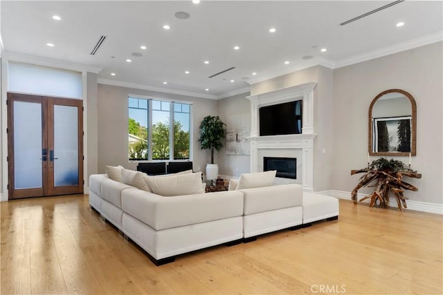 living room with crown molding, french doors, a glass covered fireplace, and light wood-style floors