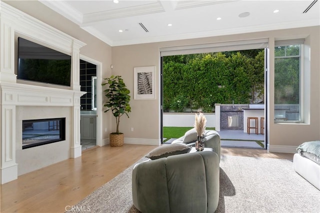 living room featuring plenty of natural light, crown molding, wood finished floors, and a high end fireplace