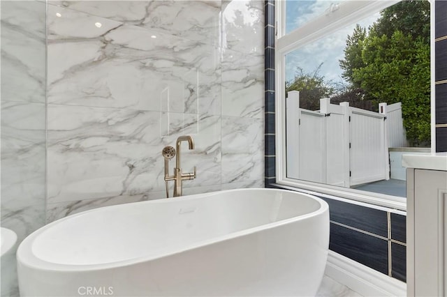 full bathroom with a freestanding tub, marble finish floor, and vanity