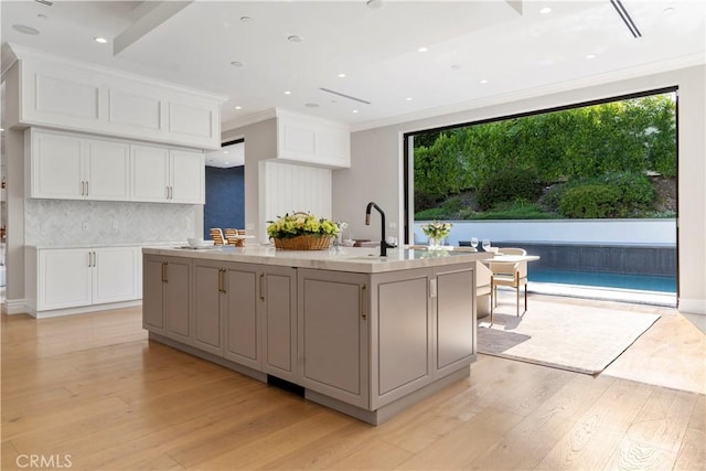 kitchen featuring decorative backsplash, white cabinets, crown molding, and light wood finished floors