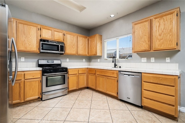 kitchen featuring light tile patterned floors, appliances with stainless steel finishes, a sink, and recessed lighting