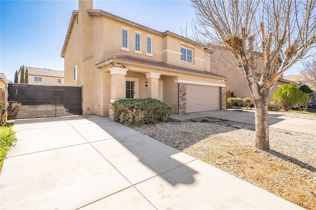 view of front facade featuring a garage, concrete driveway, a gate, fence, and stucco siding