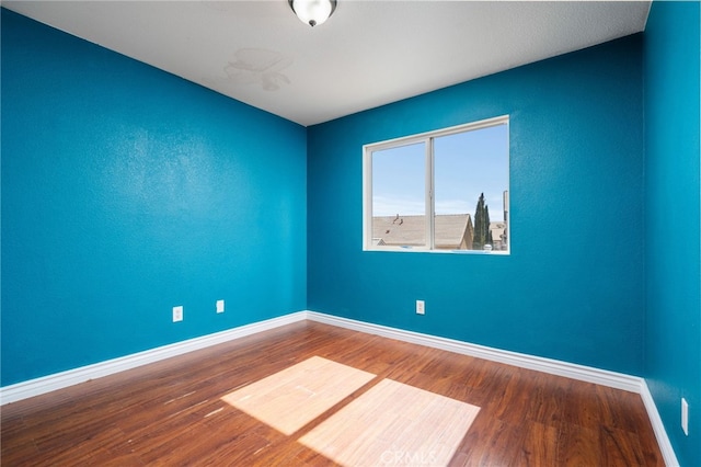 empty room with baseboards and wood finished floors