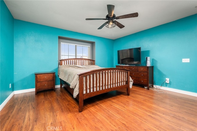 bedroom with ceiling fan, wood finished floors, and baseboards