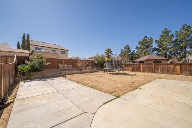 view of yard featuring a patio area, a fenced backyard, and a trampoline