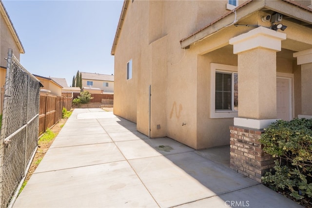 view of side of property with stucco siding, a fenced backyard, and a patio