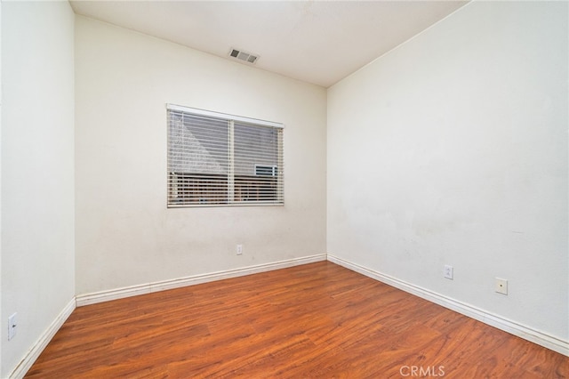 empty room with visible vents, baseboards, and wood finished floors