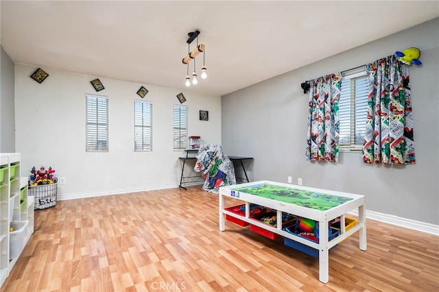 rec room with baseboards and wood finished floors