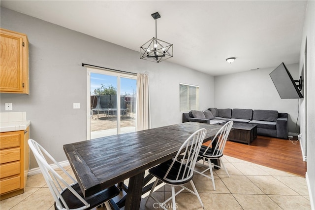 dining room featuring baseboards, an inviting chandelier, and light tile patterned floors