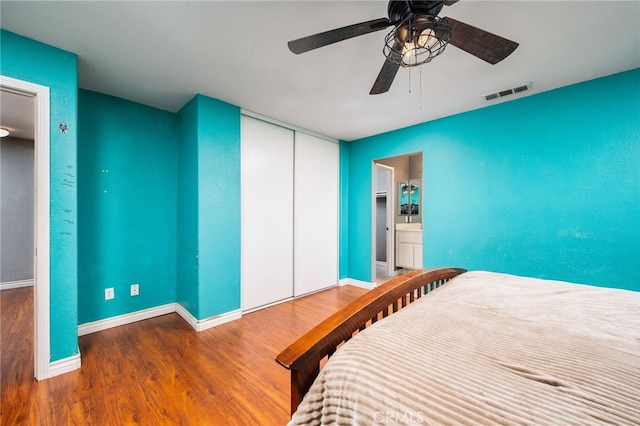 bedroom featuring a closet, wood finished floors, visible vents, and baseboards