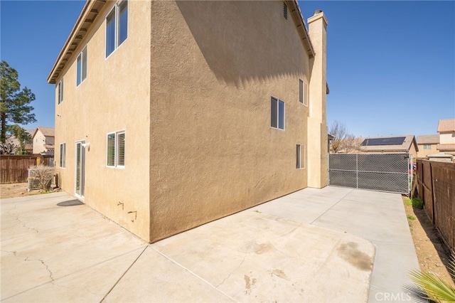 view of side of property featuring a fenced backyard, a patio, and stucco siding