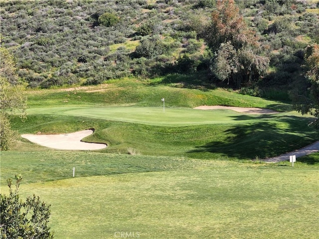 view of home's community with view of golf course and a lawn