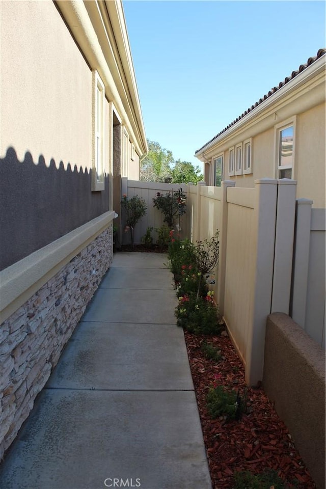view of side of property featuring a patio area, fence, and stucco siding