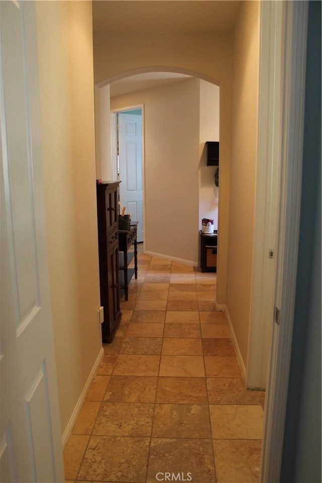 hall with arched walkways and baseboards
